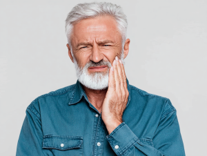 Un uomo di mezza età con la mano sulla guancia perché ha mal di denti